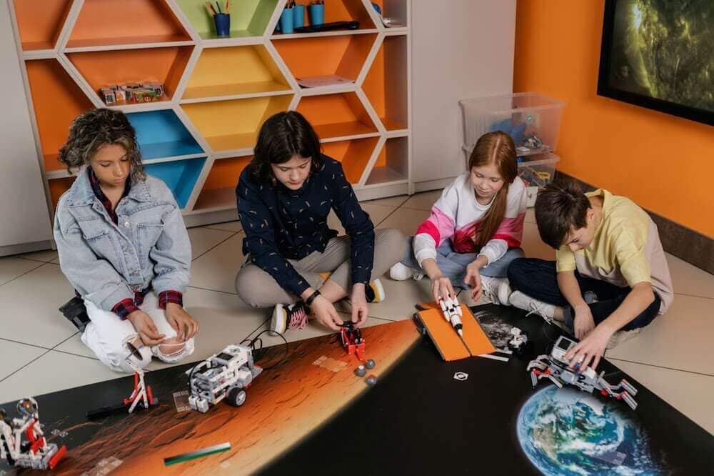 Group of 4 kids sitting on the floor building robots from LEGOs