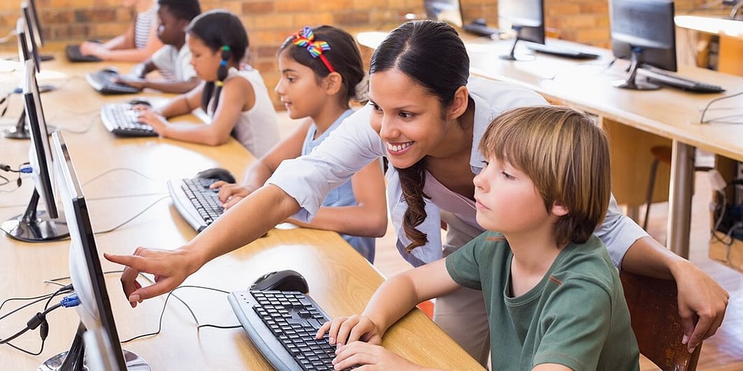 Female teacher pointing to a screen a student is using