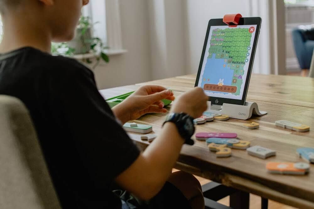 boy at a table playing a game on a tablet