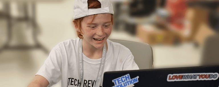 Young boy at a laptop smiling while playing Minecraft